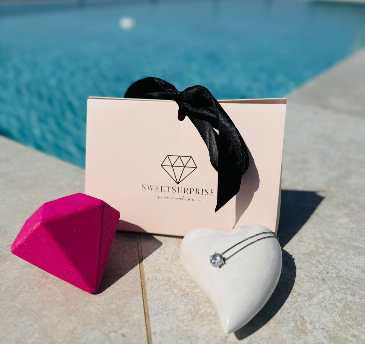 Coffret Sweet Surprise avec bombe de bain et collier en argent au bord de la piscine